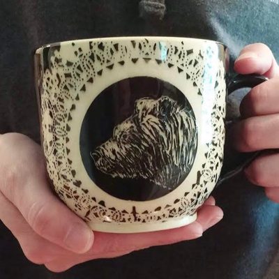 Hand holding a mug with a bird-head illustration