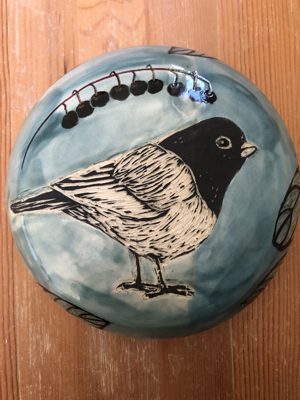Round dish with a chickadee and berries illustration