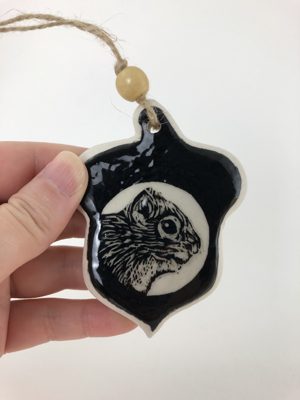 Ornament with a squirrel illustration against a moon
